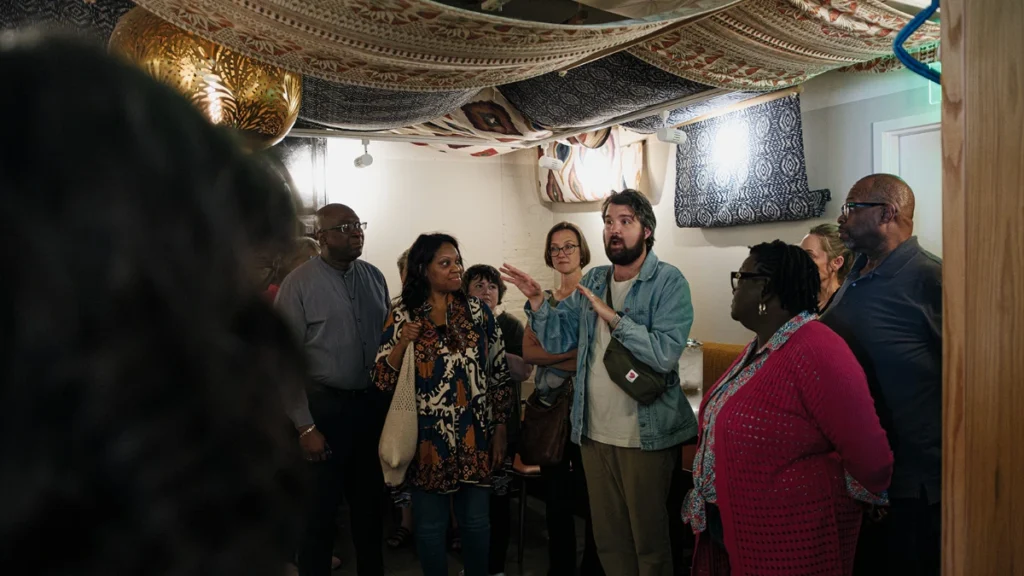 group of people from vatious backgrounds in a room with beautiful textiles handing from the ceiling